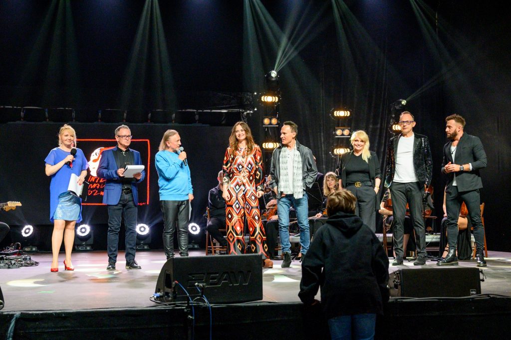 Na scenie stoją jurorzy 16. Małopolskiego Festiwalu Piosenki "Integracja malowana dźwiękiem", od lewej: prowadzący galę, Marek piekarczyk, Ania Rusowicz, Jerzy Grunwald, Adrianna Biedrzyńska, Maurycy Polaski, Wojtek Sokolnicki.